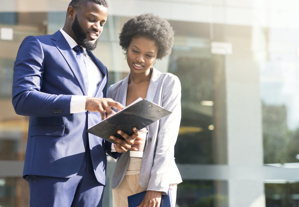 Couple of african american business partners working while standing outdoors